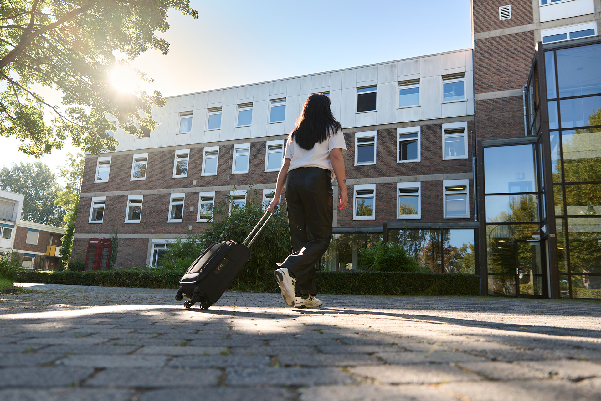 Ein Mädchen zieht einen schwarzen Koffer hinter sich her.