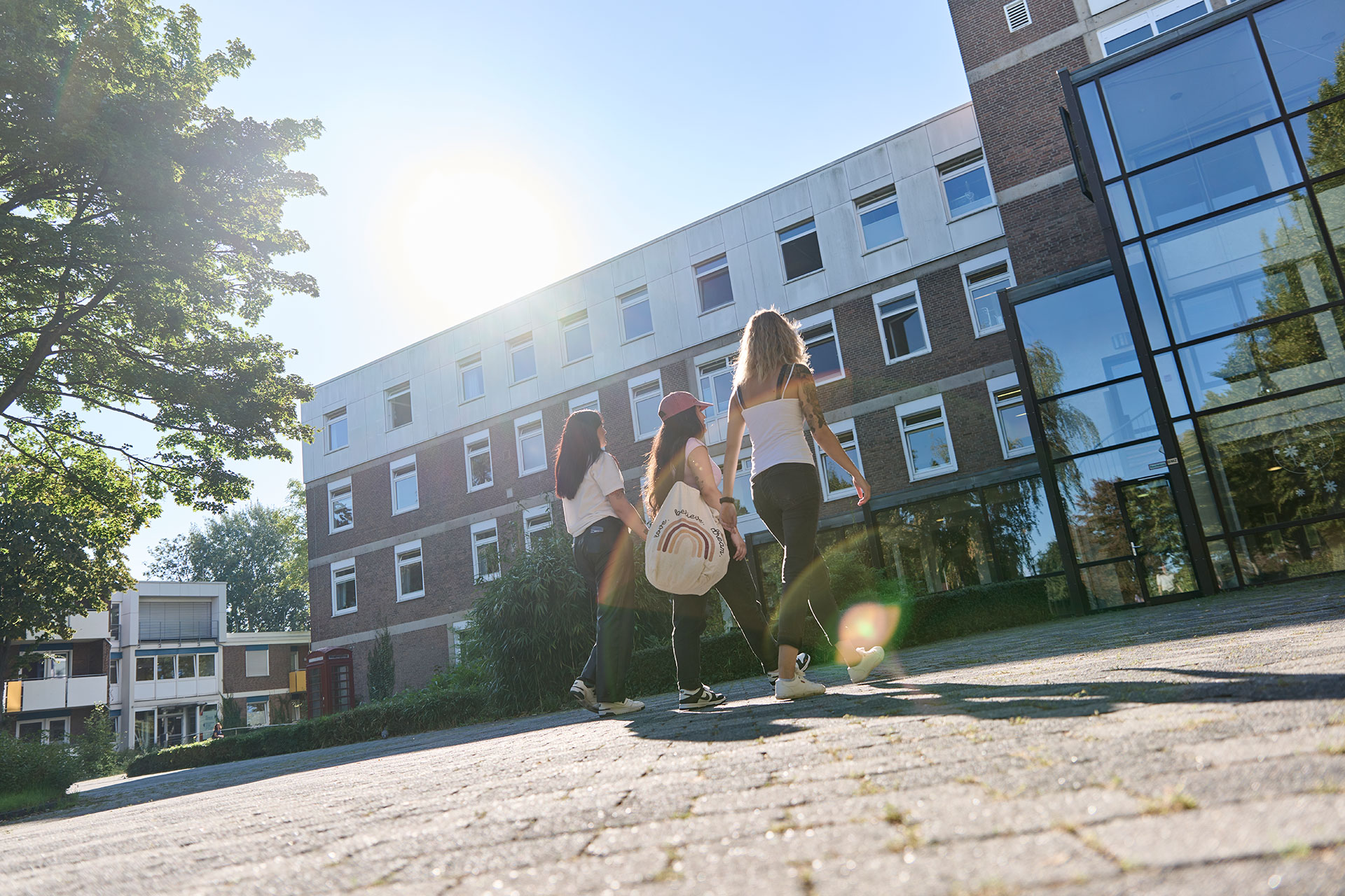 Drei junge Frauen laufen auf das Klinikgebäude zu.