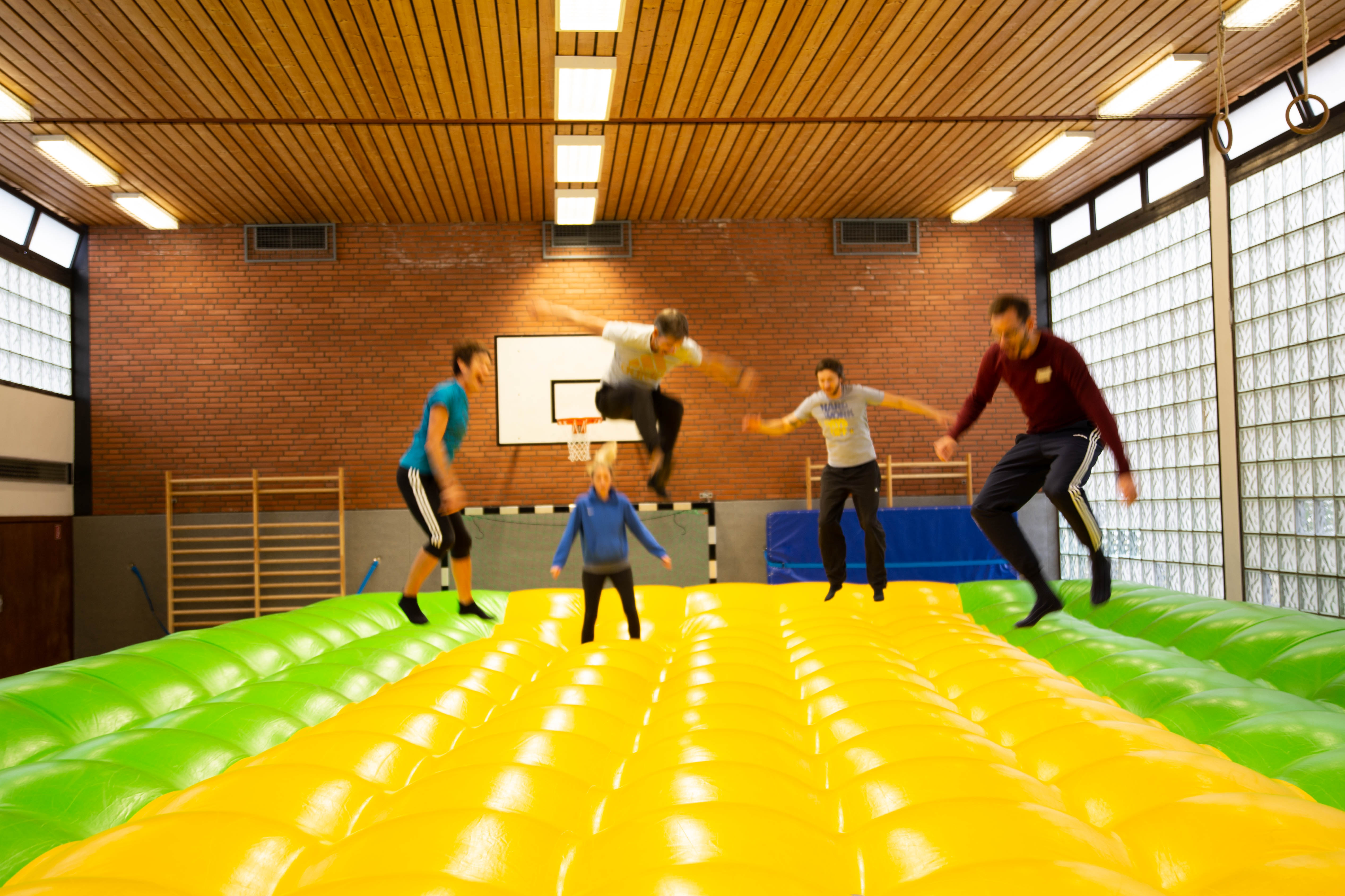 Patientinnen und Patienten beim Balanzieren und Springen auf einem riesigen Luftkissen zur Schärfung des Gleichgewichtssinns.