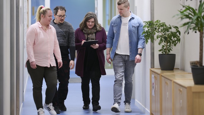 Das Bild zeigt Mitarbeitende, die gemeinsam auf ein Dokument schauen und sich darüber unterhalten.