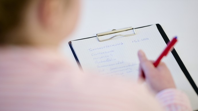 Eine Person schreibt etwas auf ein Blatt Papier
