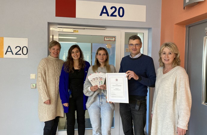 Das multiprofessionelle Team der Station A20 hält stolz die Zertifizierungs-Urkunde in der Hand.