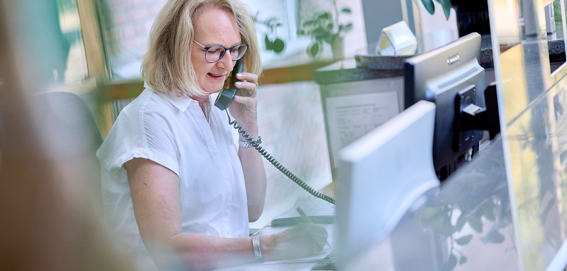 Eine Frau telefoniert und sitzt an einem Schreibtisch