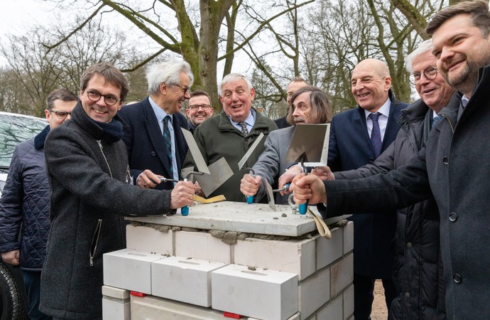 Mehrere Personen stehen um einen Grundstein herum.