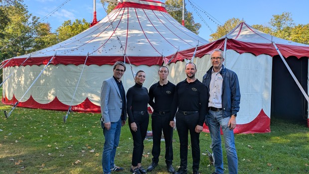 Personen stehen vor einem Zirkuszelt