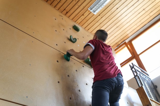 Jugendlicher klettert auf einer Kletterwand nach oben.