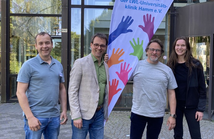 Freuen sich auf die Zusammenarbeit: Vier Medienvertreter stehen vor dem Eingangsbereich der Klinik