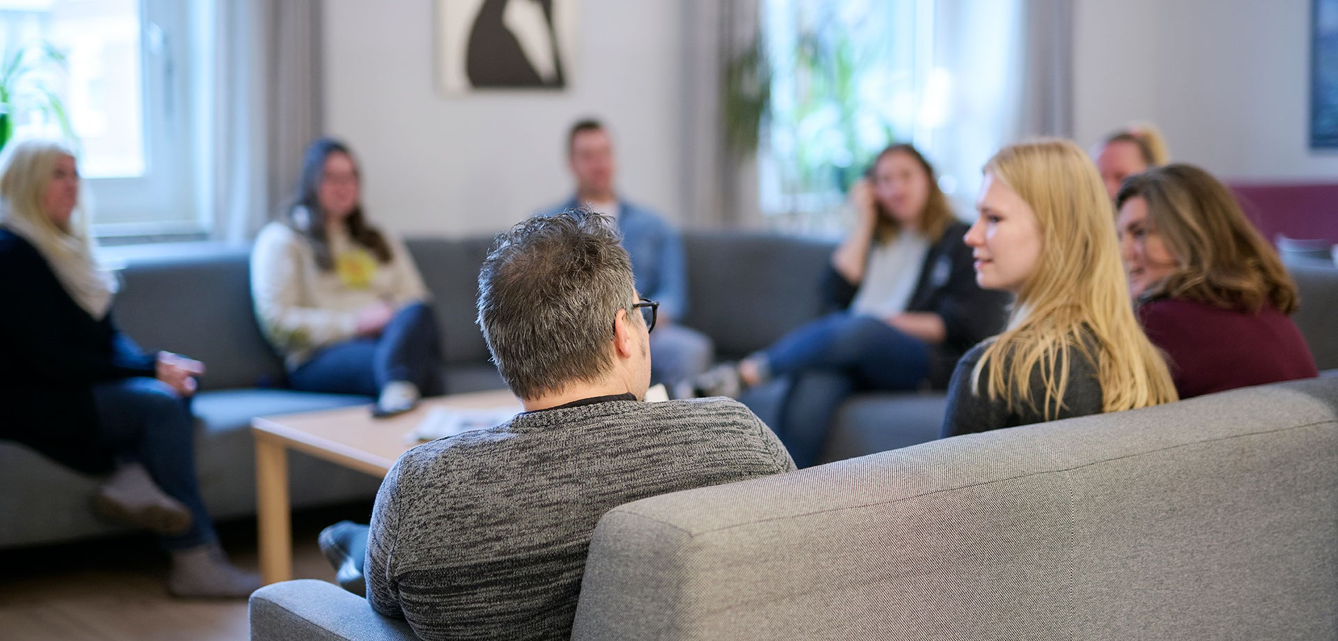 Kolleg:innen sitzen gemeinsam in einer Runde und unterhalten sich