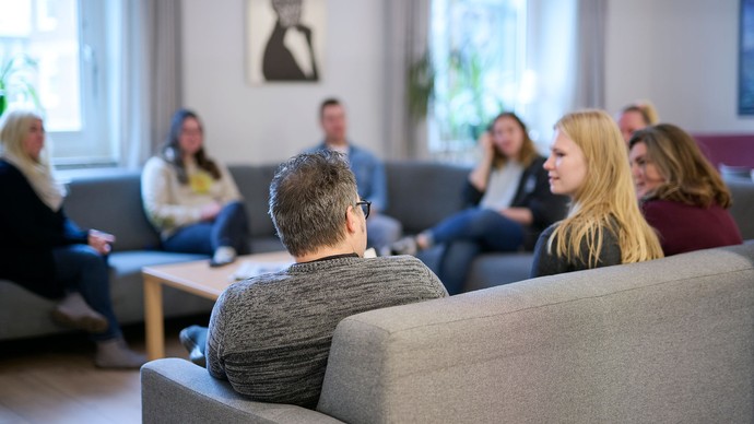 Kolleg:innen sitzen gemeinsam in einer Runde und unterhalten sich.