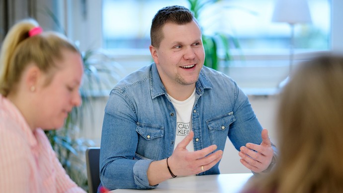 Kolleg:innen sitzen am Tisch und unterhalten sich.