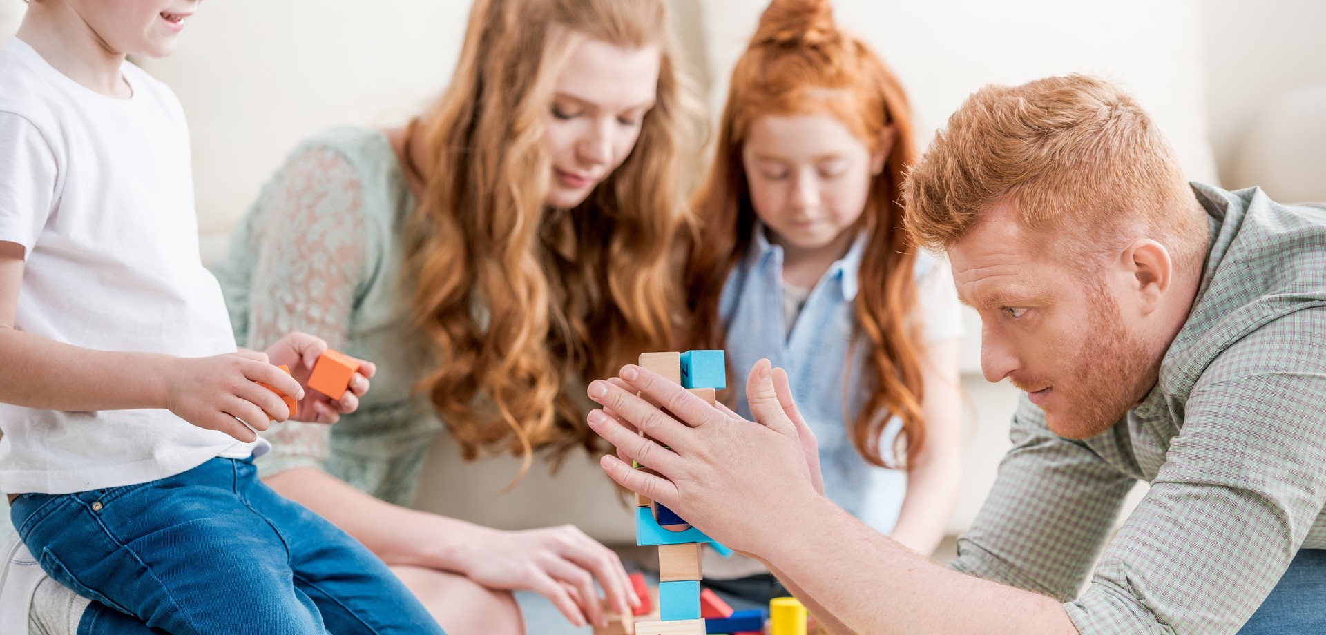 Familie spielt gemeinsam ein Spiel mit Holzwürfeln