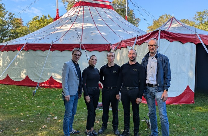 Vertreter des Circus Sperlich und der Betriebsleitung stehen vor einem Zirkuszelt. Vertreter des Circus Sperlich und der Betriebsleitung stehen vor einem Zirkuszelt.